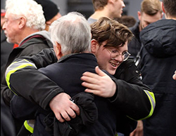 Two men hugging and smiling in a church lobby