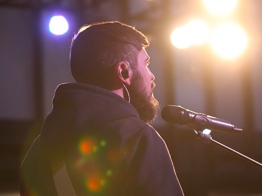 Behind shot of a singer on stage being lit up by stage lights